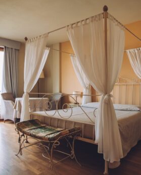 Bedroom in soft light colors. Big comfortable double bed in elegant classic interior