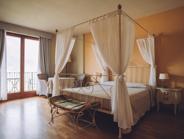 Bedroom in soft light colors. Big comfortable double bed in elegant classic interior